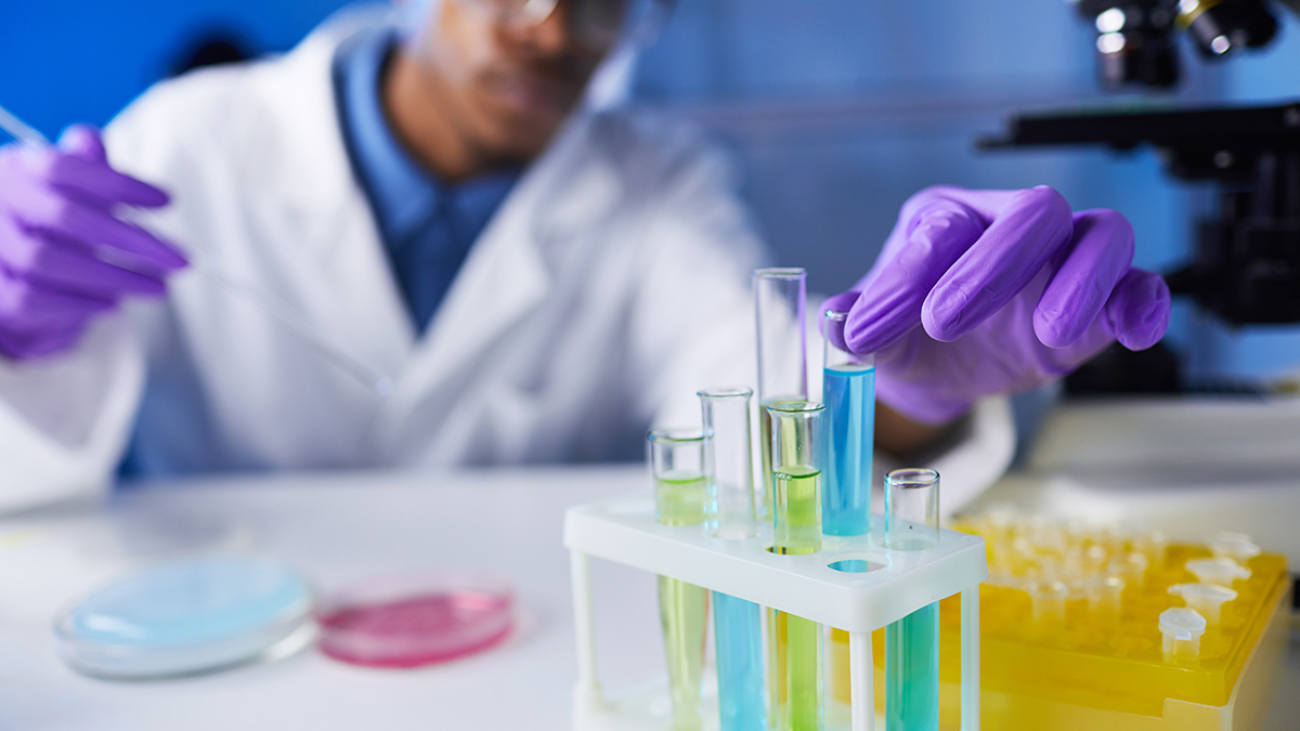 Close up of young African-American man holding test tube samples while working on medical research in laboratory, copy space