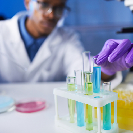 Close up of young African-American man holding test tube samples while working on medical research in laboratory, copy space