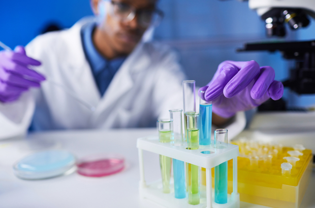 Close up of young African-American man holding test tube samples while working on medical research in laboratory, copy space