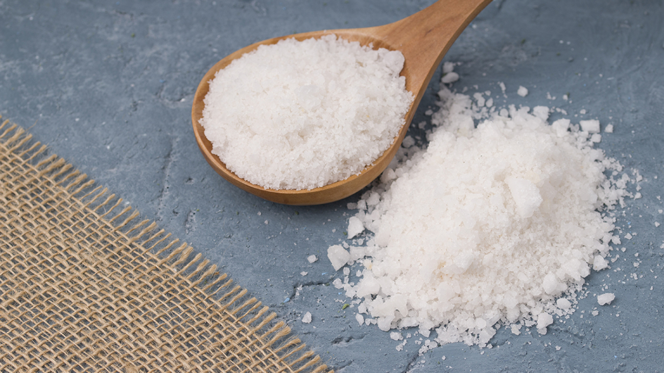 Crystals of large sea salt in a wooden spoon  on concrete background