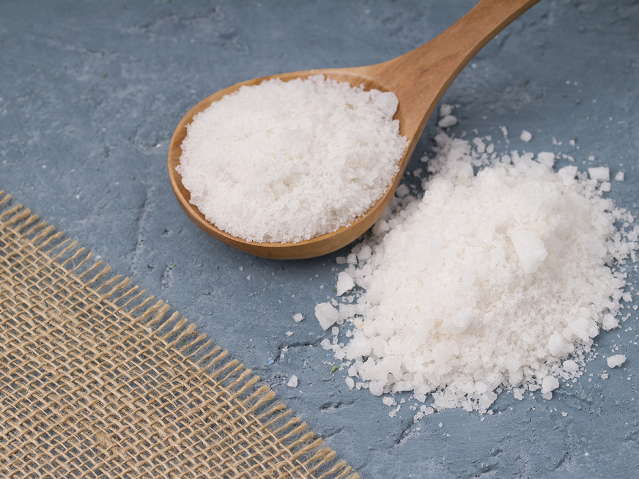 Crystals of large sea salt in a wooden spoon  on concrete background