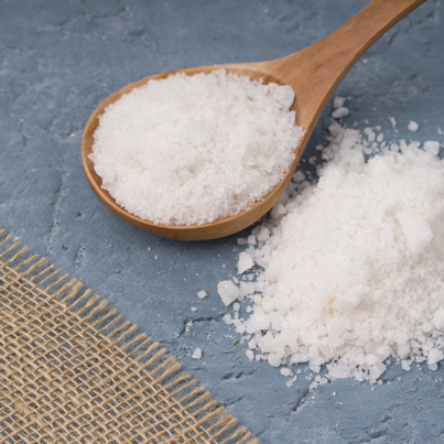 Crystals of large sea salt in a wooden spoon  on concrete background